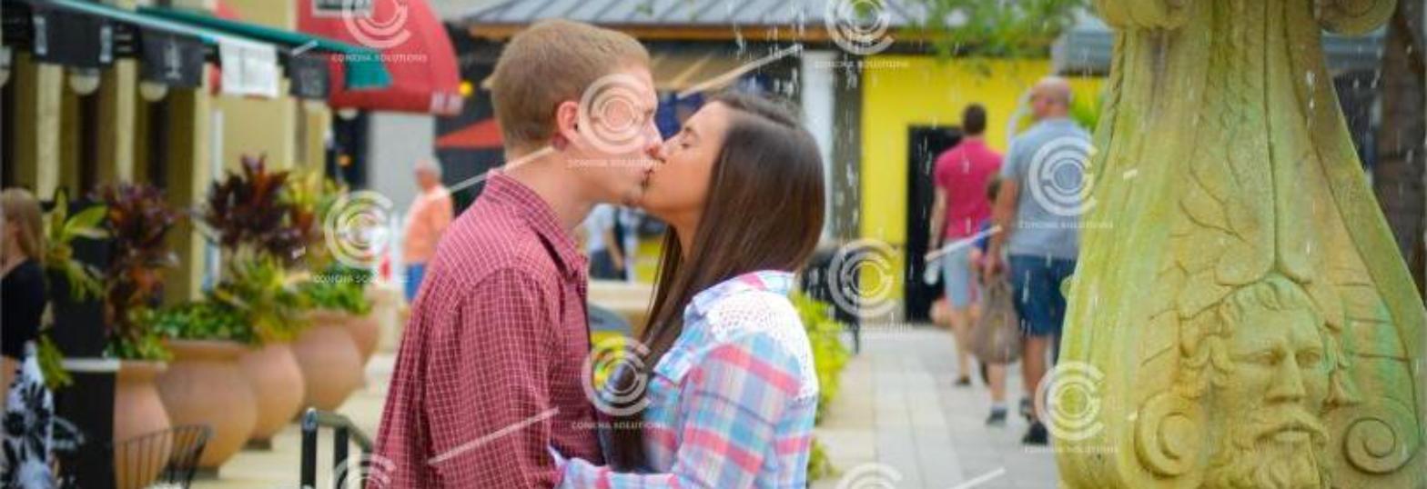 Engagement portrait at a West Palm Beach fountain, taken candidly mid-kiss