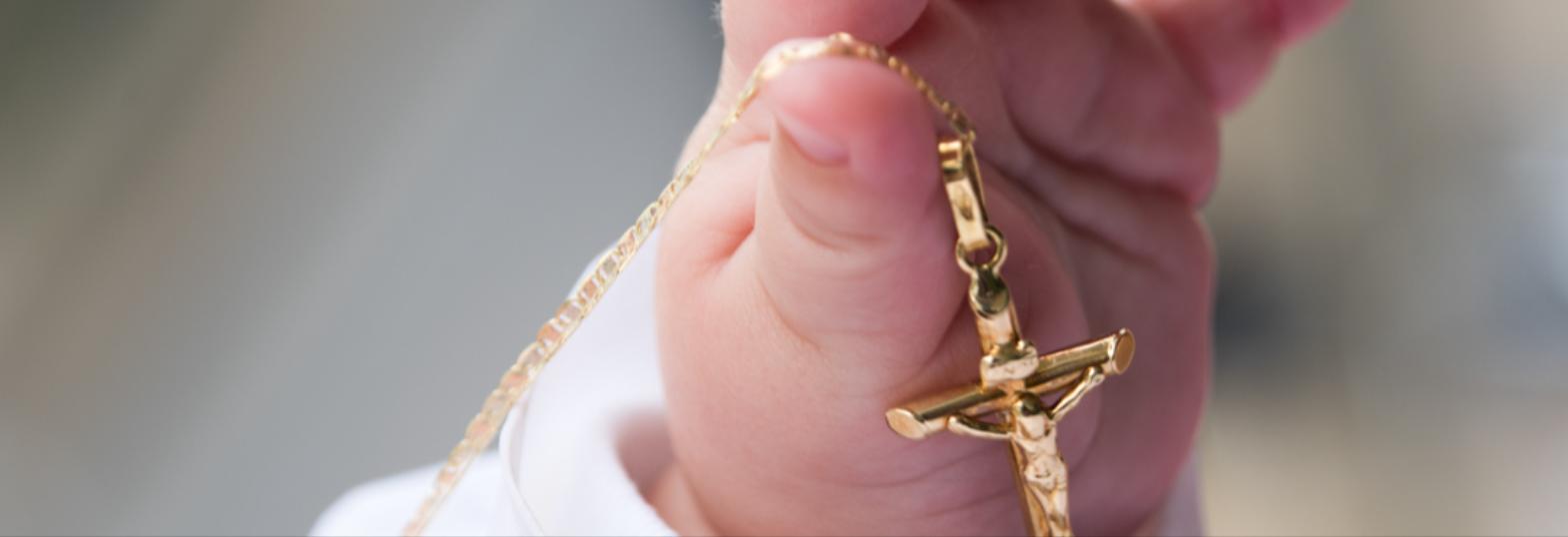 Baby's hand holding a gold crucifix pendant, close-up — West Palm Beach family photography by Concha Solutions
