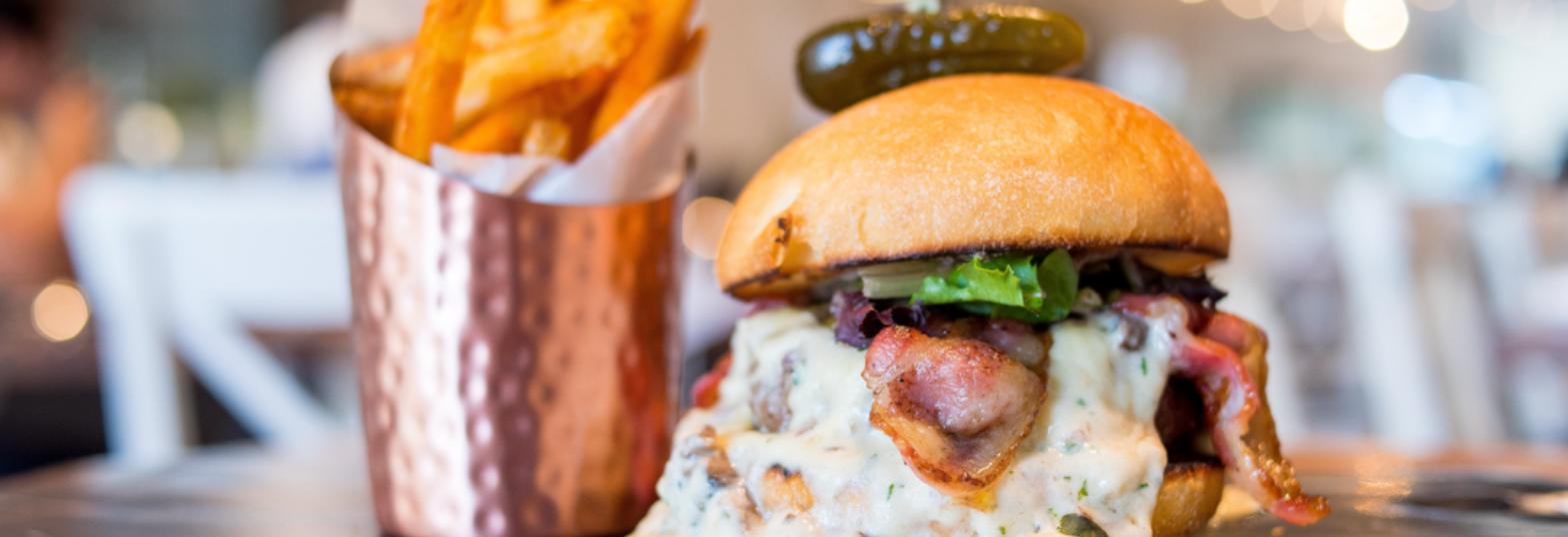 Loaded burger with fries in a copper cup, plated at a West Palm Beach restaurant